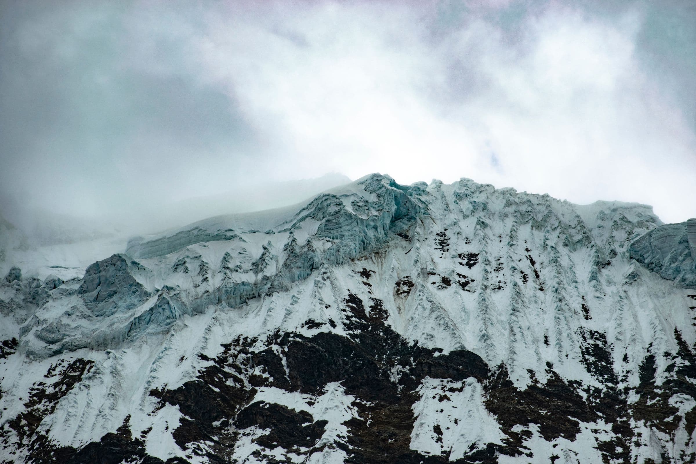Breathtaking view of snowy Andes mountain peak with clouds in winter.