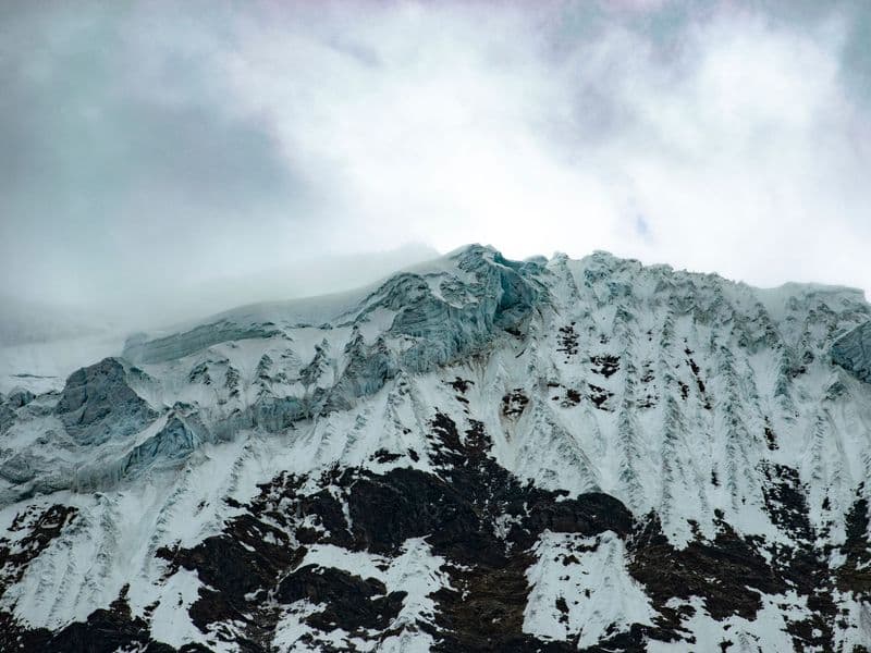 Breathtaking view of snowy Andes mountain peak with clouds in winter.