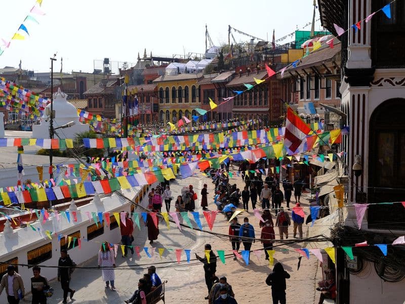 Colorful prayer flags adorn a busy street scene in Kathmandu, Nepal, showcasing urban life and cultural vibrancy.