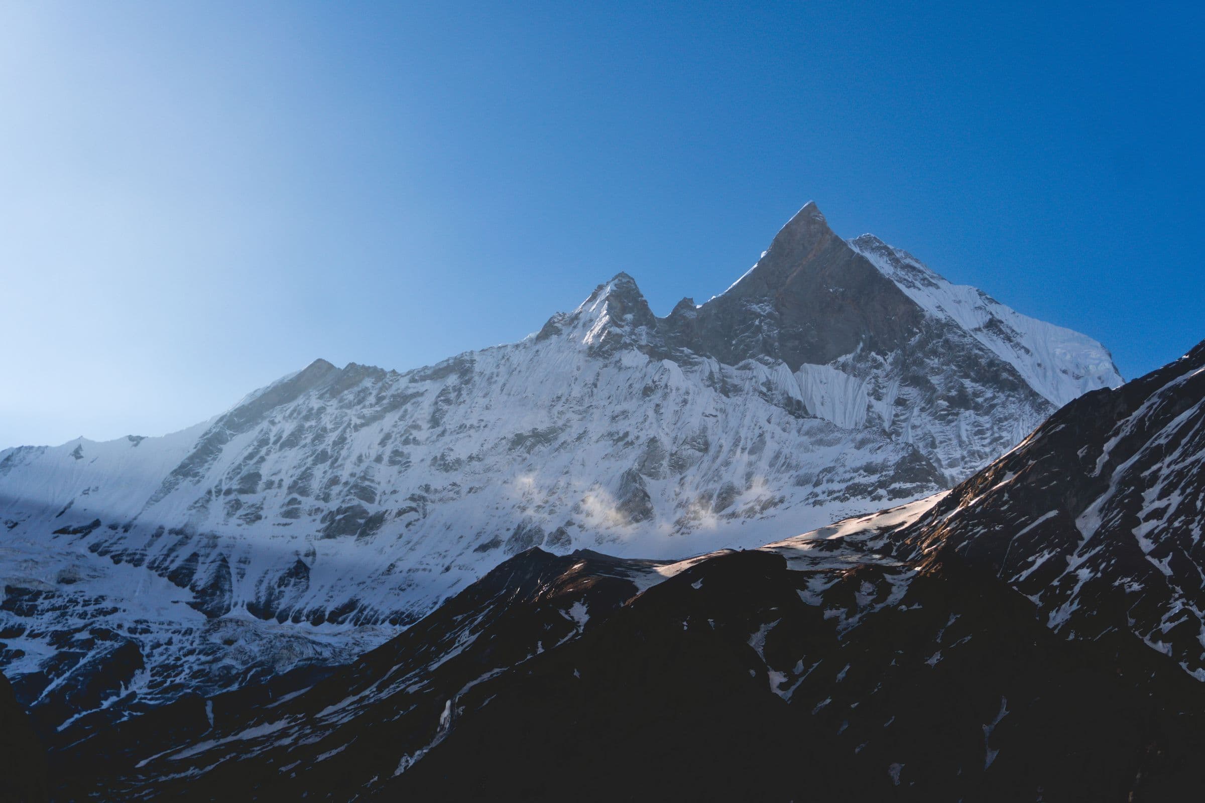 Breathtaking sunrise view of Machapuchare peak in the Himalayas, Nepal, with snow-covered slopes.