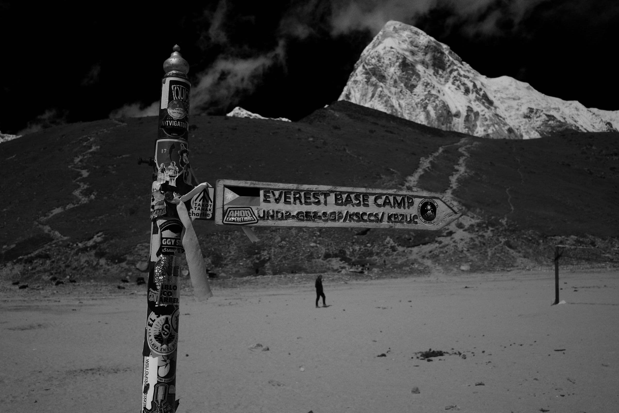 Directional sign leading to Everest Base Camp with mountains in monochrome setting.