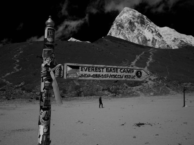 Directional sign leading to Everest Base Camp with mountains in monochrome setting.