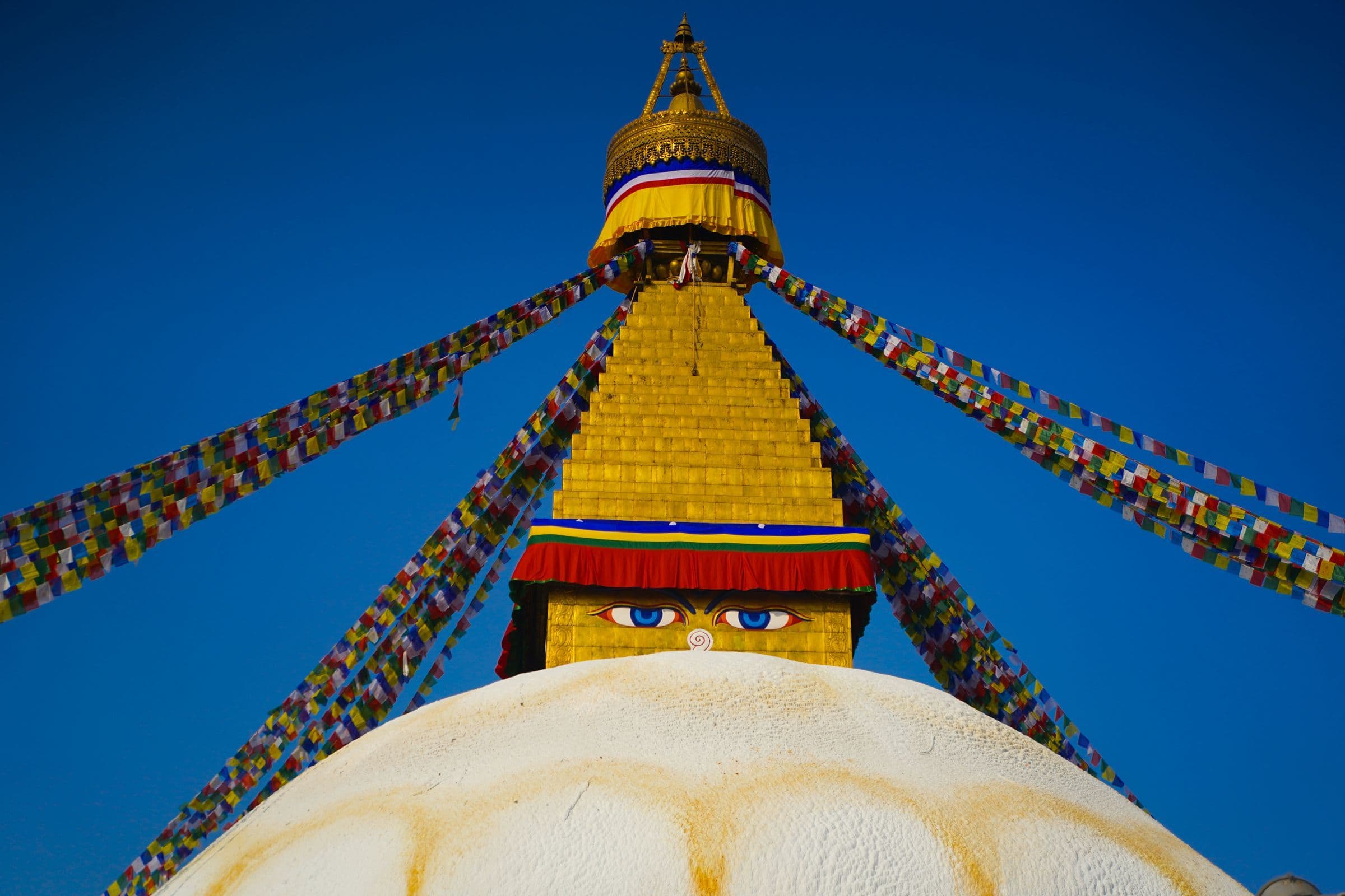 The majestic Boudhanath Stupa in Kathmandu, adorned with prayer flags under a blue sky.