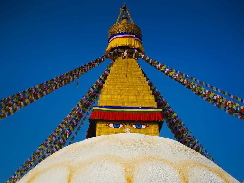 The majestic Boudhanath Stupa in Kathmandu, adorned with prayer flags under a blue sky.