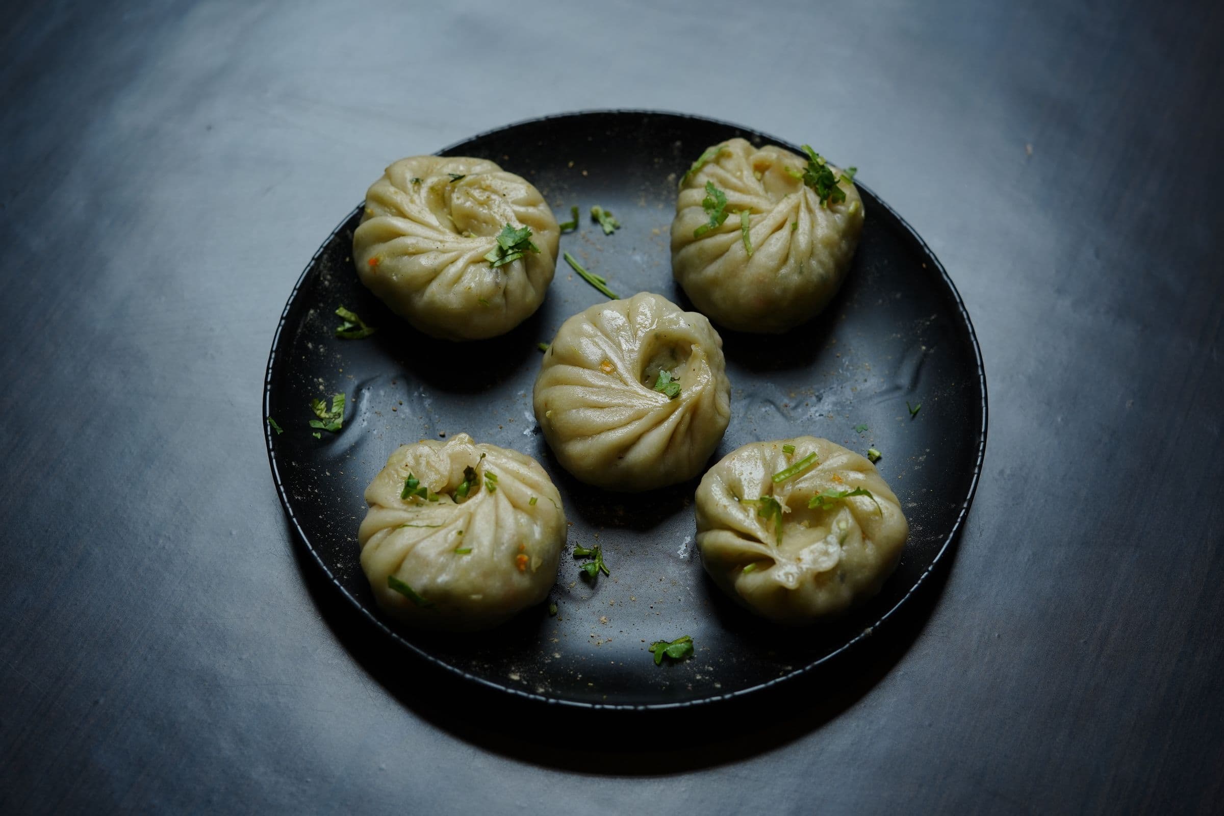 Plate of Tibetan dumplings (momos) garnished with herbs, perfect for food photography.