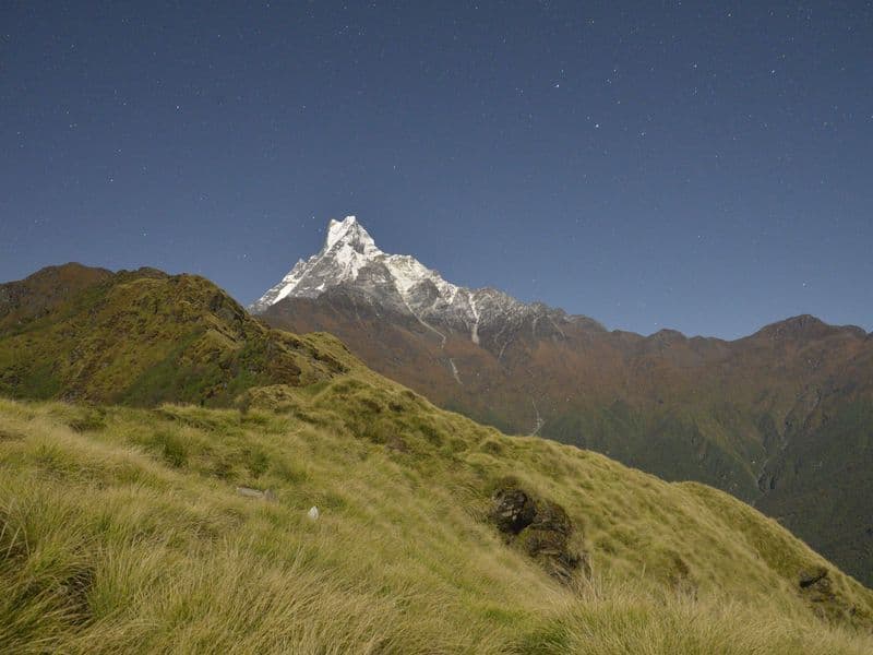 Breathtaking view of snow-capped mountains under a starry night sky, showcasing serene nature.