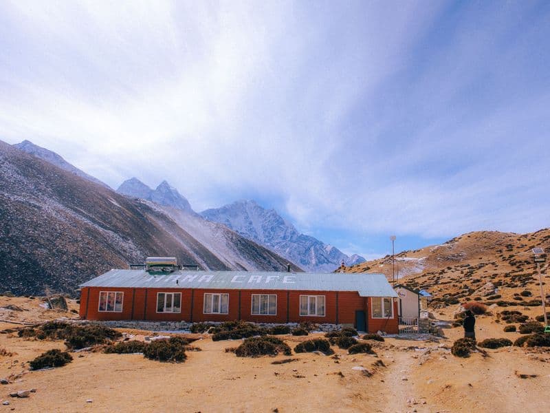 Explore the serene Himalayan landscapes with a cozy cafe nestled amidst snowy peaks.