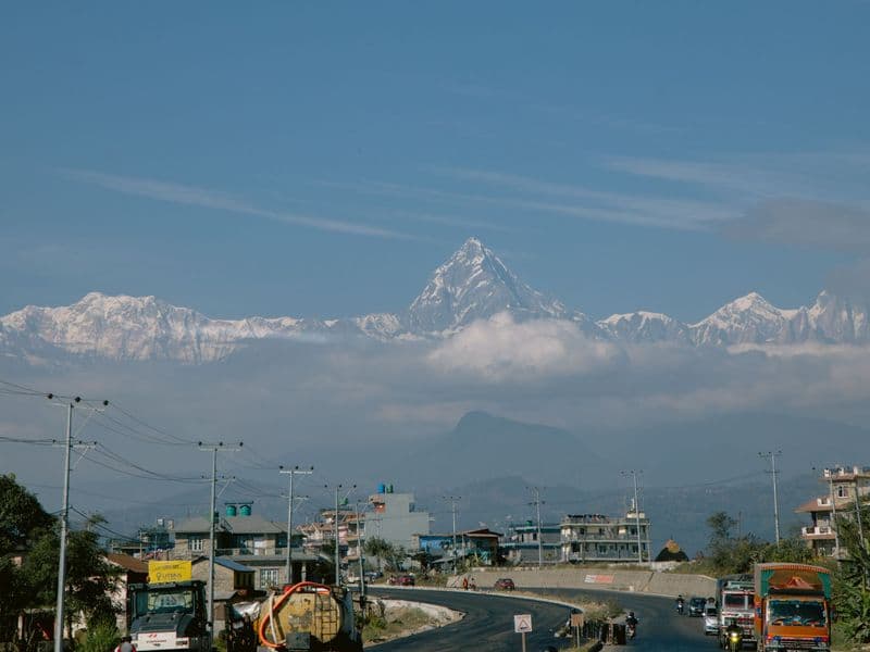Roadway in Pokhara with stunning Machapuchare mountain in the backdrop under a clear blue sky.