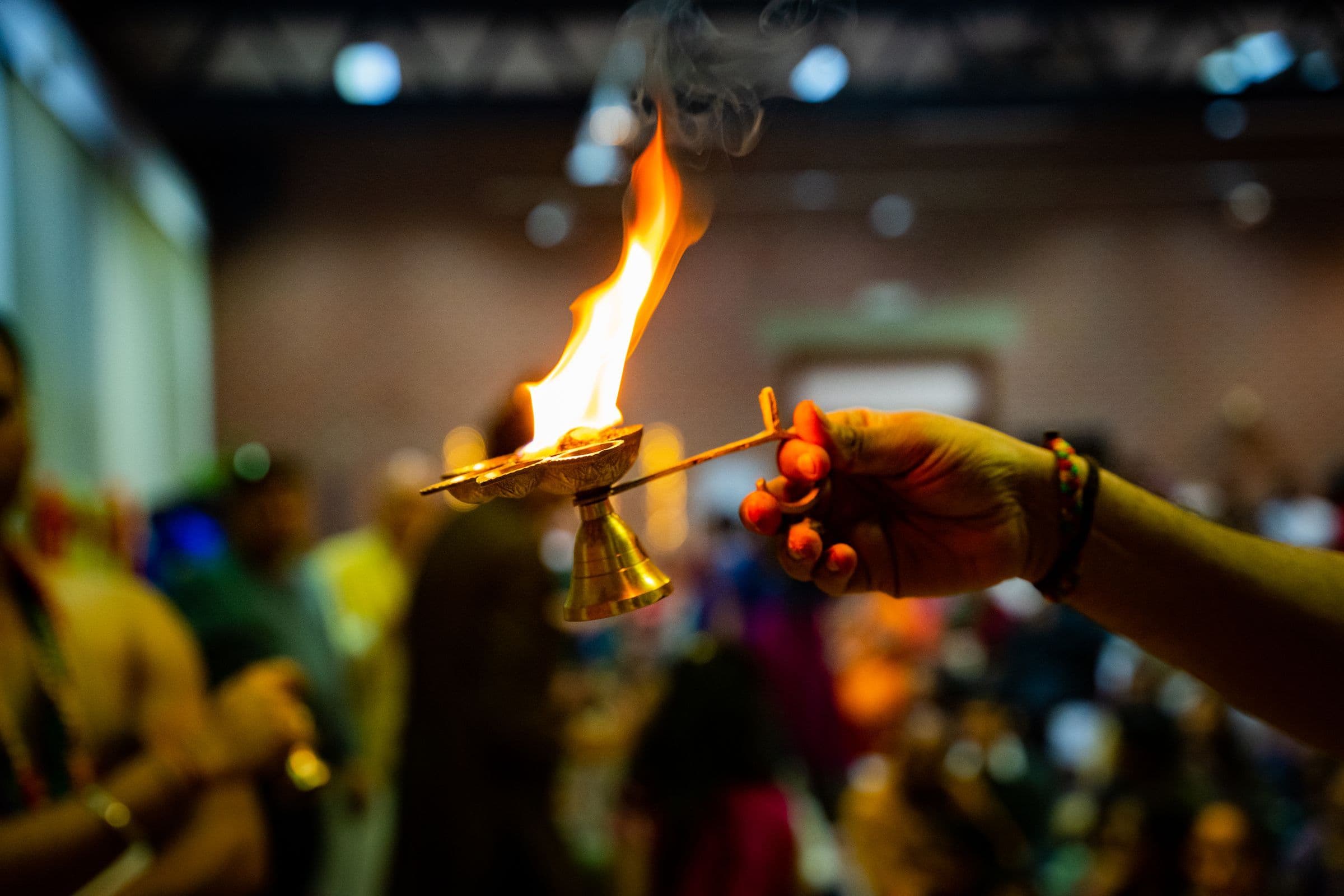 A close-up view of a person holding a ceremonial flame indoors, captured in vivid detail.