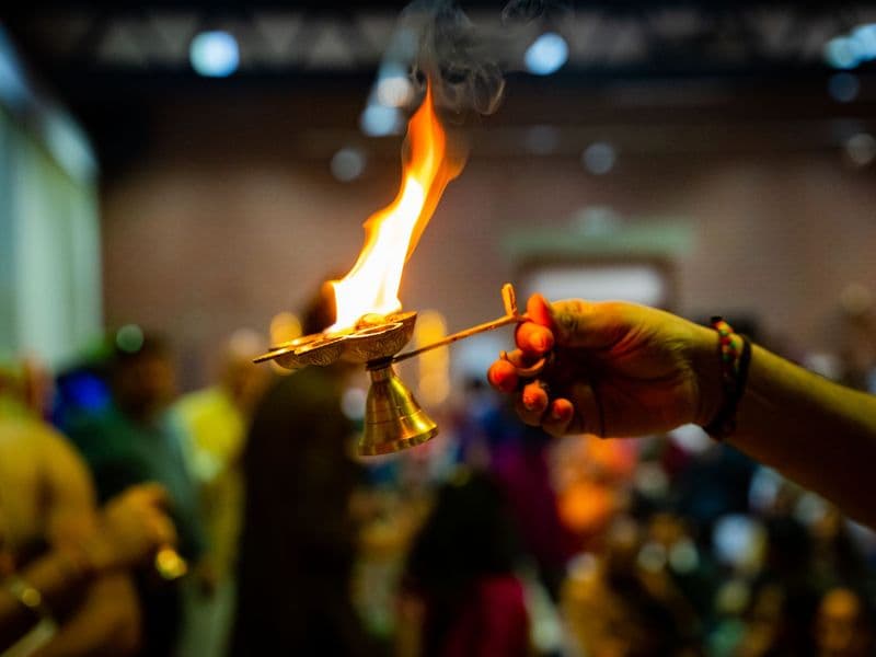 A close-up view of a person holding a ceremonial flame indoors, captured in vivid detail.