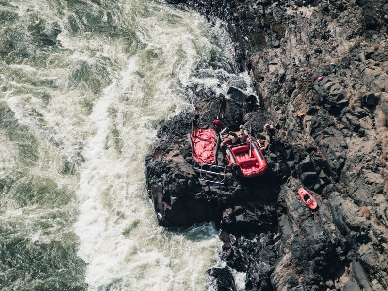 Adventure scene of red rafting gear on rocky riverside, from above.